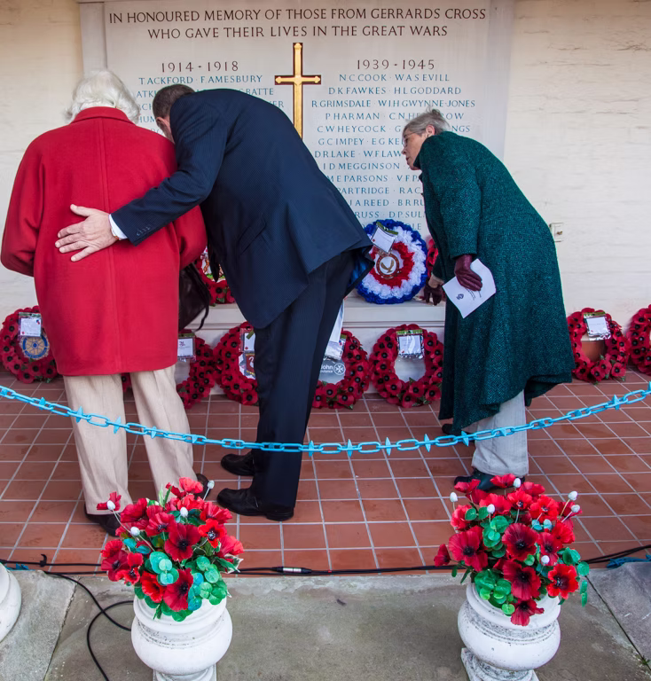 Two mourners laying poppy wreaths beneath the memorial plaque