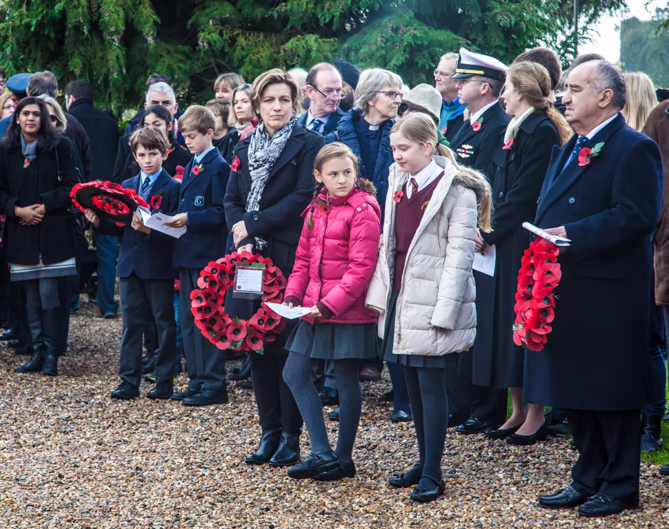 Schoolchildren and residents holding poppy wreaths at the Remembrance Day service