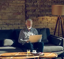 A retired professional working at a laptop