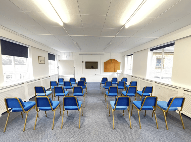 An empty bookable meeting room set out with rows of chairs