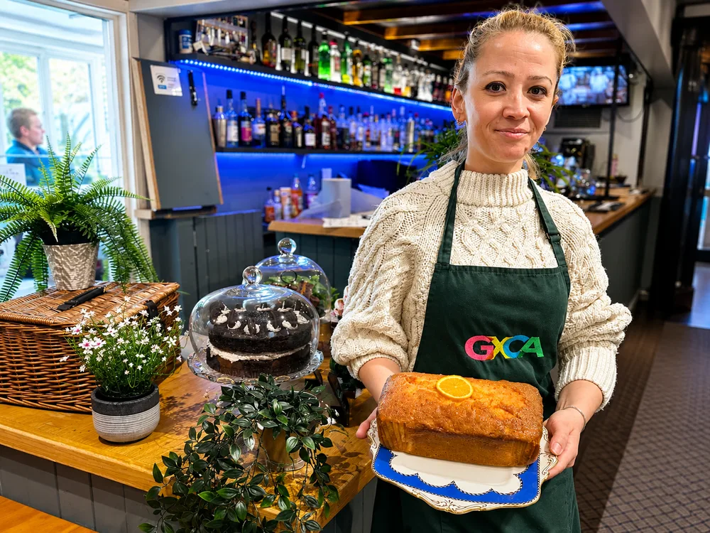 A member of the café team serving cake at the Café & Bar @GXCA counter