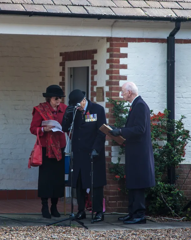 A short act of remembrance outside the Memorial Building, its whitewashed brick walls and slate roof behind