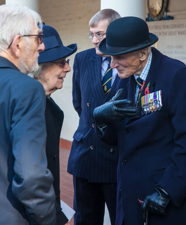 A veteran wearing his campaign medals in conversation beneath the memorial portico