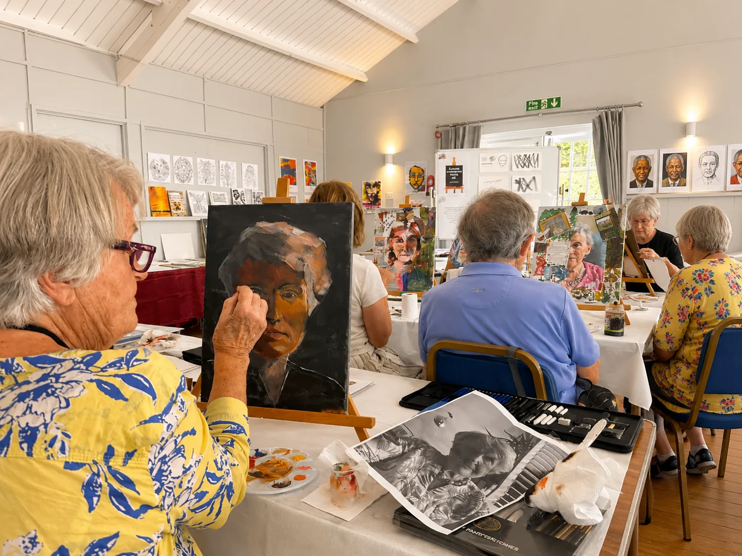 An art class painting portraits at tables in the Garden Room