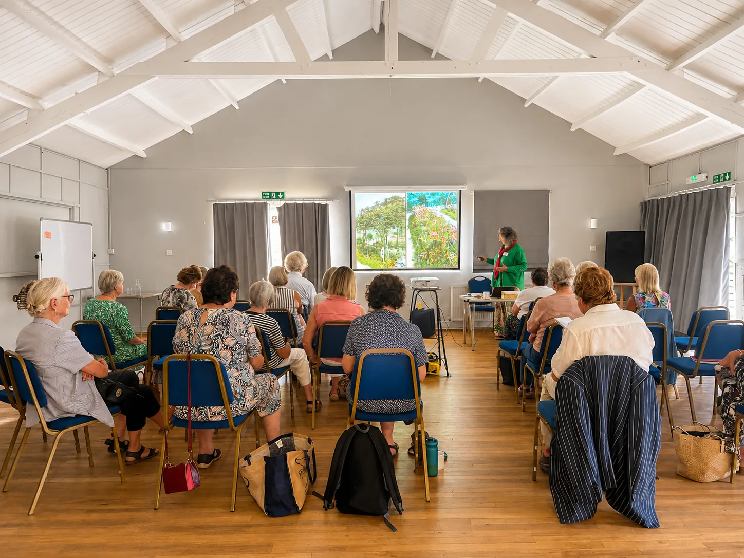 An audience seated for a talk, facing a projector screen