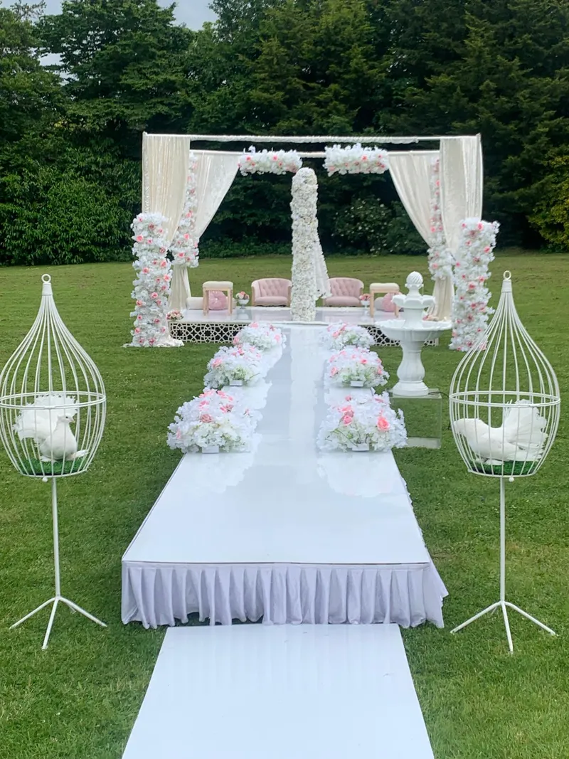An outdoor ceremony pavilion with floral drapes and a white walkway set up in GXCA’s grounds