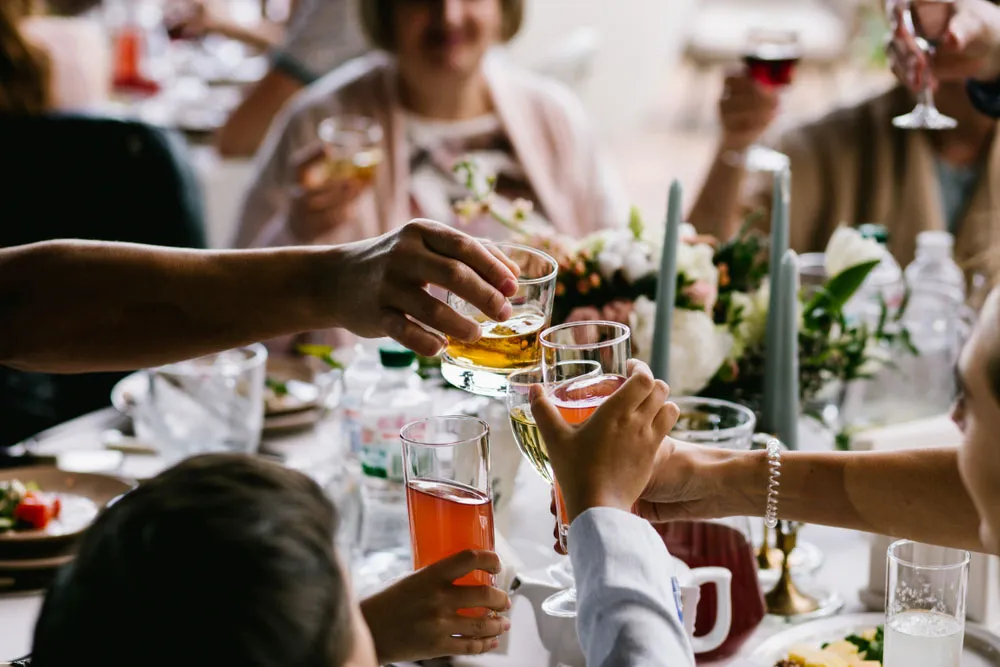 Guests raising a toast with drinks around a decorated celebration table